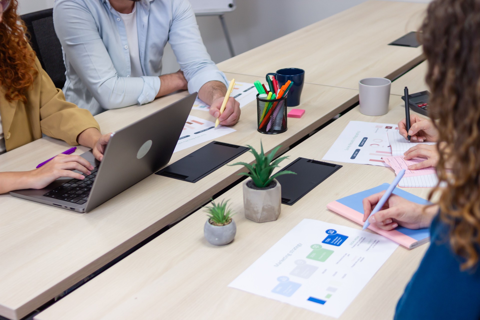 Business team analyzing data and working on laptops in coworking space